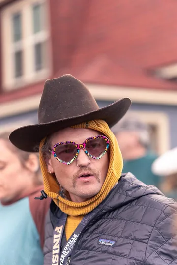 Ory Frazier after finishing the Leadville Trail 100, wearing a cowboy hat, heart-shaped sunglasses and a finisher lanyard